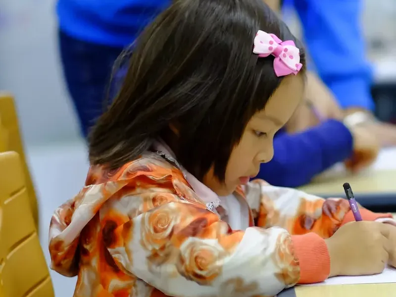 A young student writing in her notebook during class